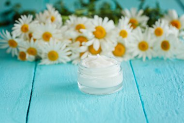 Papatya çiçek bir vücut ve yüz mavi ahşap masa üzerinde kozmetik krem