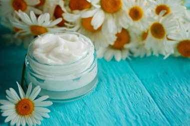 Bir vücut ve yüz mavi papatya çiçeği ile kozmetik krem