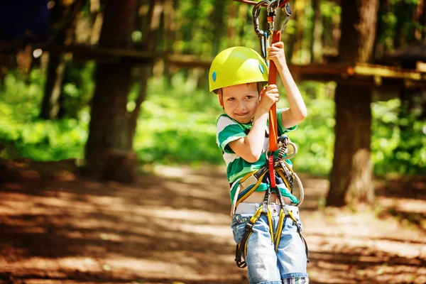 Aventura escalada parque de alambre alto - niño pequeño en curso en casco de montaña y equipo de seguridad —  Fotos de Stock