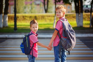 Portrait two adorable boys with backpack near pedestrian crossin clipart