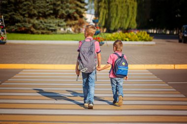 Two boys with backpack walking, holding on warm day  on the road clipart