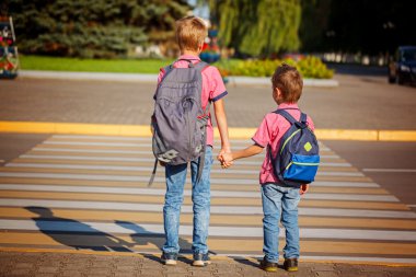 Two brothers  with backpack walking, holding on warm day  on the clipart