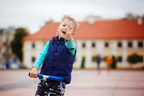 Retrato de criança pequena feliz, gosta de andar de scooter no stre — Fotografia de Stock