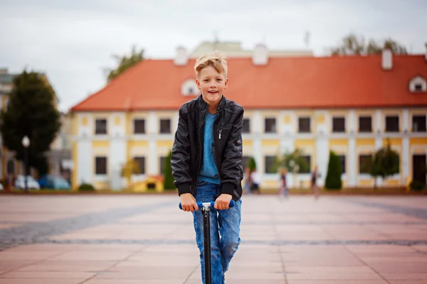 Retrato de un niño feliz, disfrute montando scooter en la calle en el campo durante el día . — Foto de Stock