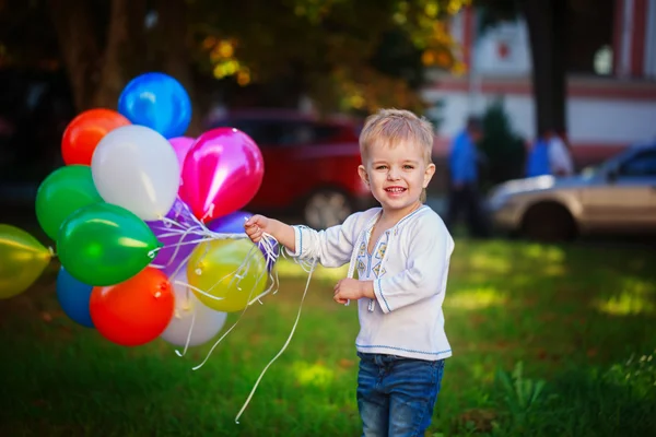Małe dziecko uśmiechający się trzymając kilka kolorowych balonów, — Zdjęcie stockowe
