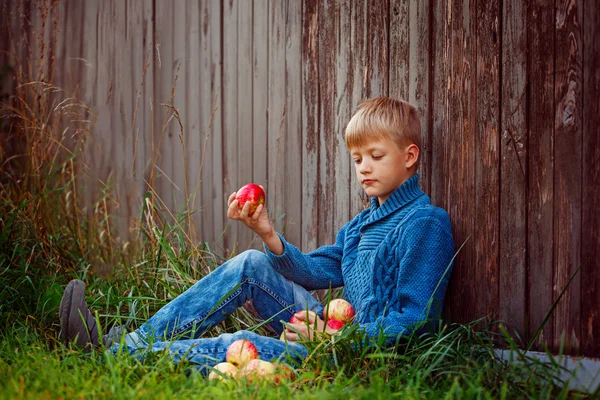 Ребенок ест красное яблоко на улице в саду — стоковое фото