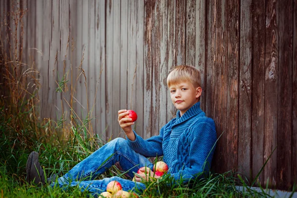 Ребенок ест красное яблоко на улице в саду . — стоковое фото