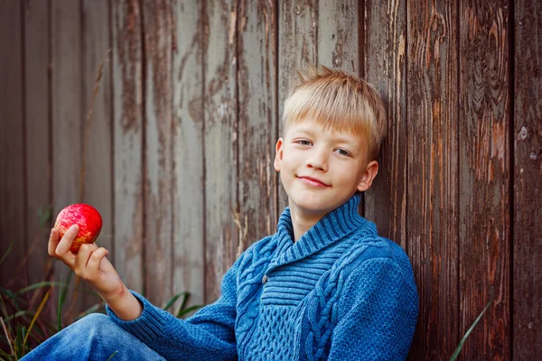 Ritratto di ragazzo felice che mangia una mela fuori in giardino — Foto Stock