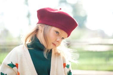 Güz parkında bordo bere takan ve örgü ören şirin sarışın kız, yakın plan..