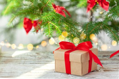 Noel ağacının altında kırmızı kurdeleli Noel hediyesi kutusu. Tatil tebrik kartı..