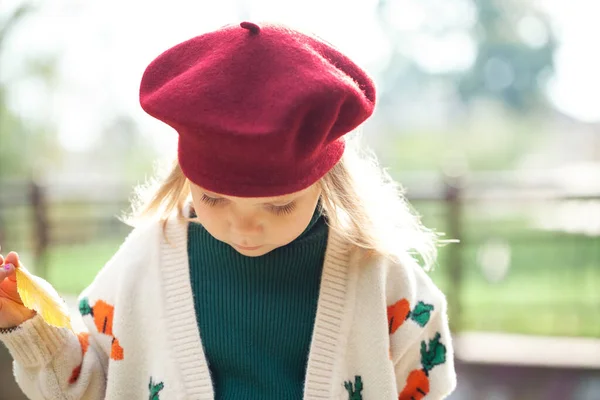 かわいいですブロンドの女の子身に着けていますバーガンディベレー帽とニットセーターで秋の公園 クローズアップ — ストック写真