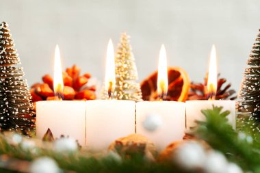 Noel arifesinde dört yanan mum ışığı ve Noel süsüsüyle köknar dallarının doğal süslemeleri..