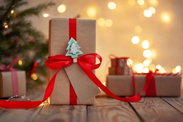 圣诞手工礼品盒 空白礼品卡放在木制桌子上 背景是一棵装饰过的圣诞树 手工制作的礼品盒 圣诞假期舒适心情的概念 — 图库照片