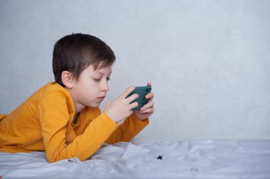 Akıllı telefonuyla bilgisayar oyununda oynayan sevimli bir çocuk. Çocuk video oyunu oynarken eğleniyor. Sosyal ve teknoloji kavramı