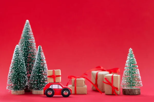 喜庆的构图圣诞红色轿车 在松树林中有一个礼品盒 许多不同的礼物都是红色背景的 新年快乐卡的概念 — 图库照片