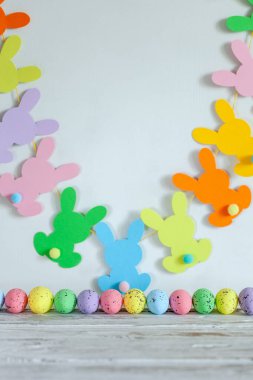 Renkli Paskalya yumurtaları ve bej arka planda el yapımı paskalya çelengi. Mutlu Paskalyalar.