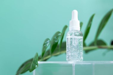 Arka planda yeşil yapraklı pipetli kozmetik şişe nemlendirici yüz serumu. Profesyonel kozmetik ürünü