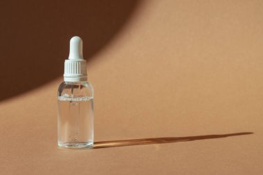 Serum için kozmetik damlası şişesi, mikiler toneri ve kahverengi arka planda emülsiyon. Cilt bakımı, hidrasyon ve beslenme oksijen kabarcıkları. Güzellik ürünü..