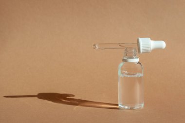 Serum için kozmetik damlası şişesi, mikiler toneri ve kahverengi arka planda emülsiyon. Cilt bakımı, hidrasyon ve beslenme oksijen kabarcıkları. Güzellik ürünü..