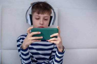 Çocuk eller oynamak ya da öğrenmek için akıllı telefonu yakın plan çekimde tutuyor. Çocuk elleri cep telefonuna bakıyor. Teknoloji kullanan çocuklar.