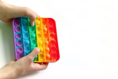 Güzel motor beceriler geliştirmek için kullanılan renkli popüler oyuncaklar, stres ve akıl sağlığı için. Popit gökkuşağı oyuncağıyla oynayan çocuk - Tik Tak 'tan 2021 yılının trendi.