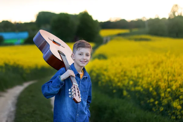 夏の道をギターで歩くポートレートハンサムな男の子 成功への道を行く若い音楽家 — ストック写真