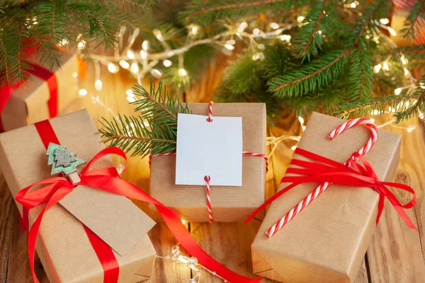 木製のテーブルの上に空の空白のギフトカードで赤いリボンを飾るクリスマス手作りのギフトボックス 手作りのギフトボックス クリスマス休暇 居心地の良い 気分のコンセプト — ストック写真