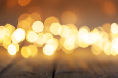 Tahta masa ve sıcak turuncu ışıklarla bulanık bokeh arkaplan. Noel ışığı arka planı bokeh.