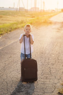 Çocuk bir bavul yaz güneşli bir günde tutar.