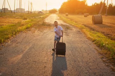 mutlu çocuk yaz güneşli bir günde bir bavulla çalıştırmak