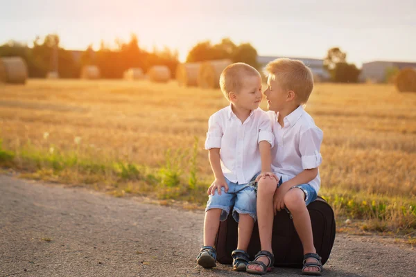 İki kardeş bir bavul yolda güneşler, yaz aylarında oturmak — Stok fotoğraf
