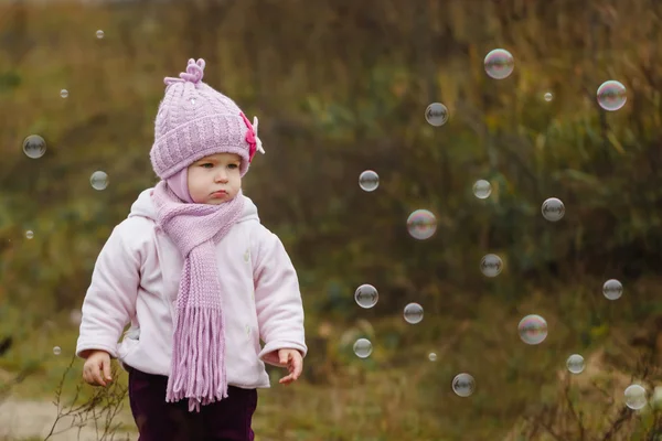 Menina bonito no parque pegando bolhas no outono dia frio — Fotografia de Stock