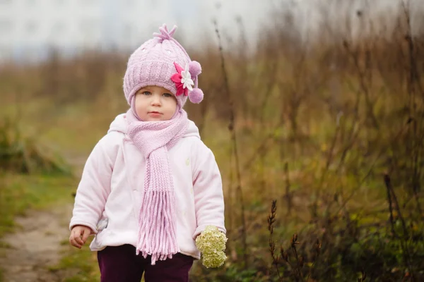 Bebê feliz menina em um chapéu rosa e cachecol ri no outono dia frio — Fotografia de Stock