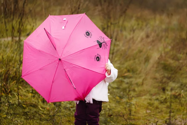 The little girl I hid under a pink umbrella in autumn park — Stock Photo, Image