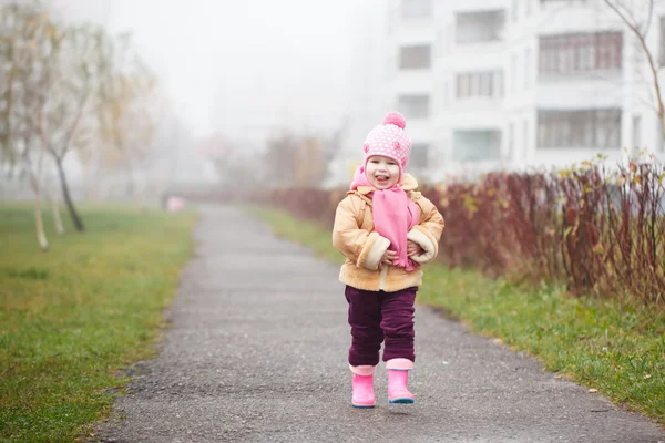 Cute little 2 years old smiing girl in a pink hat and scarf in the autumn park — Stock Photo, Image