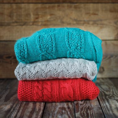 Ahşap background.square üzerinde renkli örgü kazak yığını