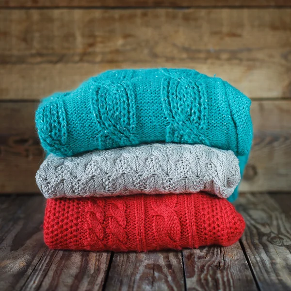 Ahşap background.square üzerinde renkli örgü kazak yığını