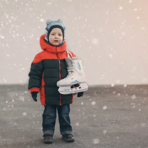 Cute little boy  holds the skates wearing warm winter clothes  g — Stock Photo, Image