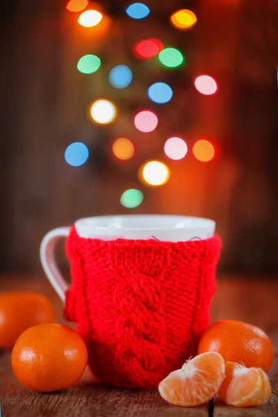 Knitted red cup with christmas lights at background — Stock Photo, Image