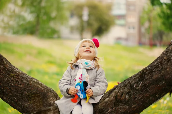 Маленькая милая забавная очаровательная девушка сидит на цветущем дереве в G — стоковое фото