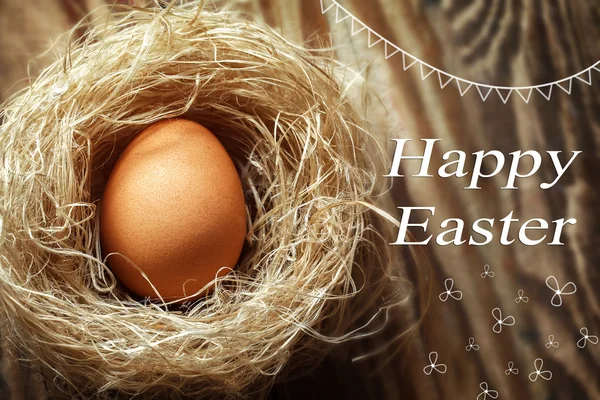 Feliz huevo de Pascua en el nido sobre fondo de madera —  Fotos de Stock
