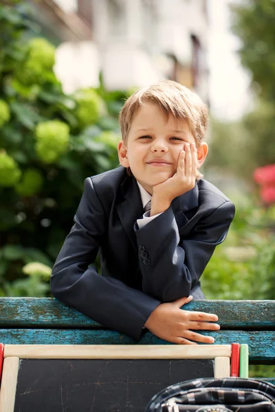 Menino da escola sorridente no parque verde, dia ensolarado — Fotografia de Stock