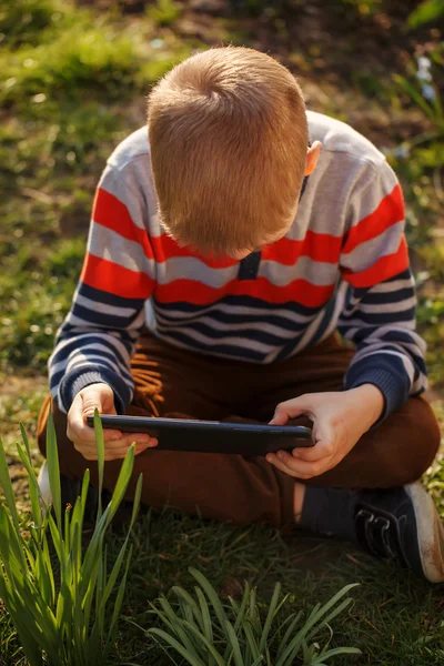 Liten unge absorberas i sin tablett, utomhus — Stockfoto