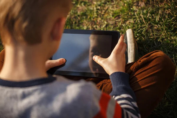 Крупным планом руки ребенка закрываются, держа в руках цифровой планшет для pla — стоковое фото
