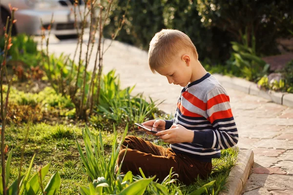 Young boy outdoors on the grass at backyard using his tablet com — Stock Photo, Image