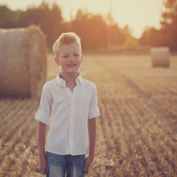 Glücklicher netter Junge spielt im Weizenfeld an einem warmen Sommertag — Stockfoto