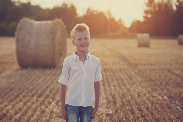 Glücklicher netter Junge spielt im Weizenfeld an einem warmen Sommertag — Stockfoto