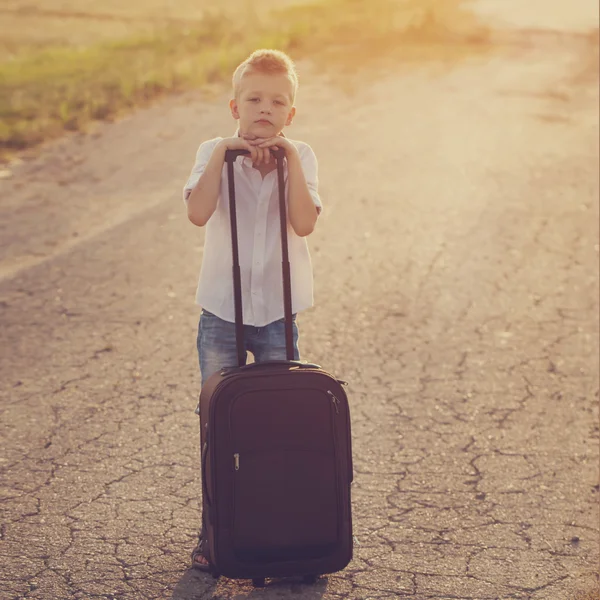 Der Junge hält einen Koffer an einem sonnigen Sommertag — Stockfoto