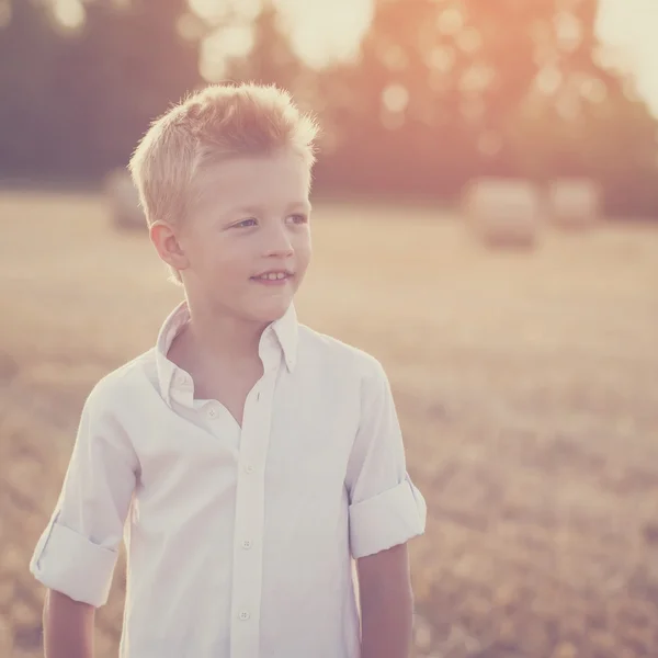 Portrait of a happy child  in the sunny day in a field — Stock Photo, Image