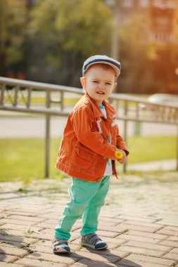Küçük şirin çocuk bir ceket ve bir kap içinde bir karahindiba içinde tutar 